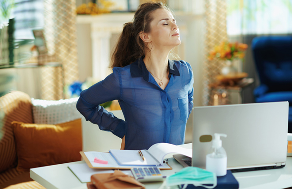 Woman-sitting-at-desk-holding-back-in-pain